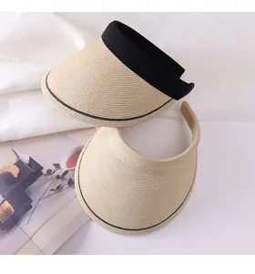 Detail of two straw sun visors with wide brims in khaki and black, perfect for summer.