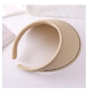 Detailed macro view of a beige woven straw sun visor with elegant black stitch detailing.