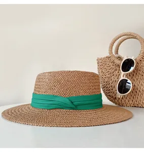 Close-up of women's flat-top straw sun hat featuring a vibrant green fabric ribbon band