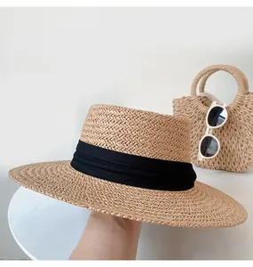 Close-up of a classic flat-top straw sun hat with a black ribbon band for summer beach vacations