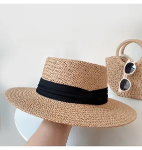 Close-up of hand-woven flat top straw hat with elegant black band for summer sun protection