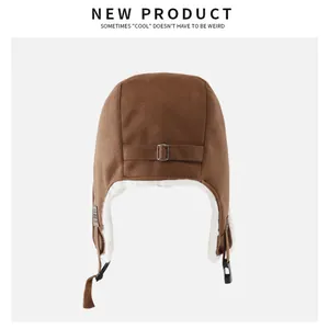 Detailed view of brown suede winter trapper hat with white fleece lining and buckle.