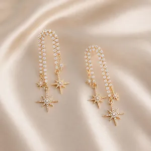 Close-up of 18K gold-plated long chain earrings with zircon star charms