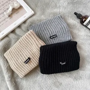 Primo piano di tre fasce in maglia nei colori beige, grigio e nero con trama in lana