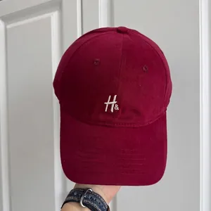Primer plano detallado de una gorra de béisbol vintage granate con bordado de letra H