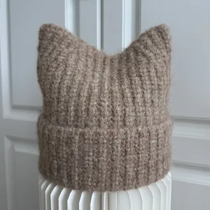 Close-up of a cozy brown knitted beanie with cute cat ears and chunky rib texture
