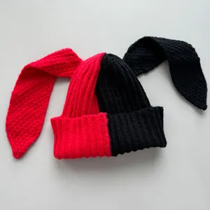 Close-up detail of split-color red and black knitted beanie with long rabbit ears