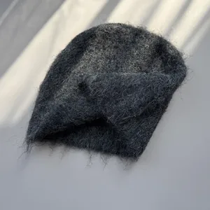Detailed macro view of dark grey fuzzy mohair texture on a warm knitted winter beanie
