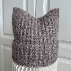Detail of a cozy brown knitted beanie with cute cat ears featuring soft ribbed texture