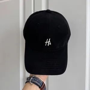 Detalle de una gorra de béisbol retro negra de alta calidad con bordado de letras H& blancas