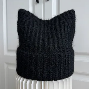 Detailed view of a black fuzzy knitted beanie with cute cat ears and ribbed texture
