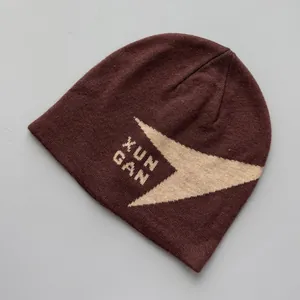 Vista detallada de un gorro de punto deportivo marrón con texto y patrón XUN GAN