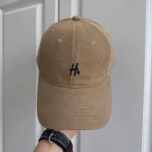 Vista detallada de una gorra de béisbol de algodón caqui con un bordado H azul marino