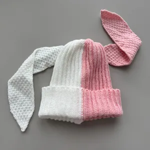 Close-up of a two-tone pink and white knitted beanie with adorable long bunny ears