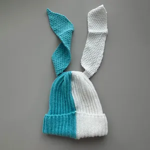 Macro detail of a two-tone knit beanie featuring long bunny ears in teal and white.