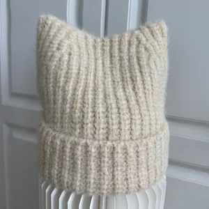 Detailed view of a beige knitted cat ear beanie showing fuzzy mohair wool texture.