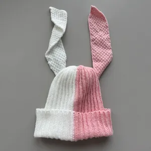 Detailed texture of pink and white color-block knitted beanie with long bunny ears