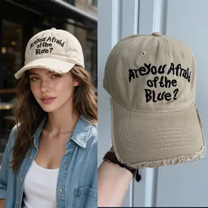 Détail d'une casquette beige avec texte brodé noir et bord usé pour un style vintage