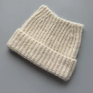 Detail shot of a soft beige knitted beanie with cute cat ear design and ribbed texture.
