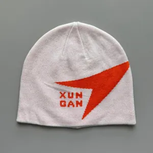 Primer plano de un gorro de punto rosa con diseño gráfico naranja y detalles del texto XUN GAN