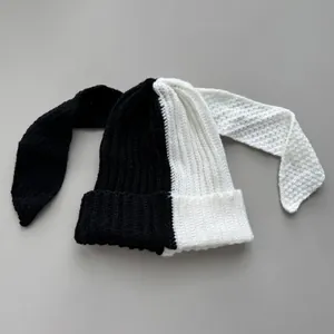 Detail of black and white split knit beanie with long bunny ears shown on grey background