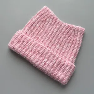 Detailed close-up view of a pink knitted cat ear beanie featuring a soft chunky rib texture