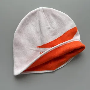 Detalle de la textura del gorro de punto deportivo blanco y naranja para invierno.
