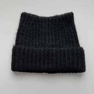 Close-up macro view of a black knitted beanie featuring cute cat ear shapes for winter
