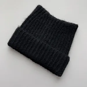 Detailed top-down view of a black knitted cat ear beanie showing soft wool texture and shape.