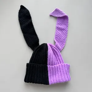 Detail of two-tone knitted beanie featuring long rabbit ears and split color design.