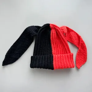 Close-up detail of a two-tone black and red knitted beanie featuring long bunny ears