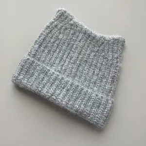 Close-up detail of a grey knitted cat ear beanie showing soft wool texture and rib-knit.