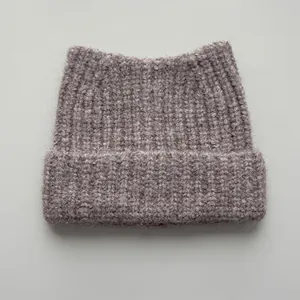 Close-up detail of a soft brown knitted winter beanie with cute cat ear design peaks