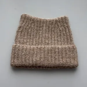 Detailed view of a cozy beige knitted beanie with cute cat ear design for winter warmth