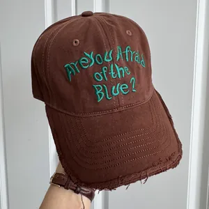 Vue détaillée d'une casquette marron avec broderie verte et bordure de visière effilochée.