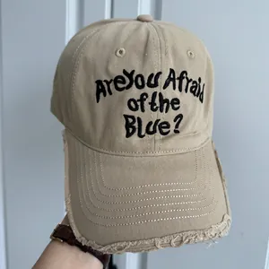 Vue détaillée de la casquette beige avec broderie noire et bordure effet usé sur le devant