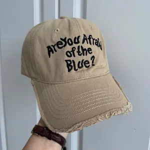 Détail d'une casquette de baseball kaki de style usé avec du texte brodé en noir.