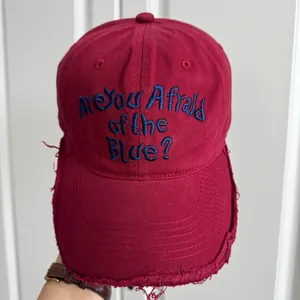 Détail d'une casquette bordeaux vieillie avec broderie bleue
