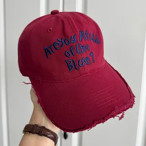 Gros plan sur une casquette bordeaux vieillie avec broderie bleue 'Are You Afraid of the Blue'