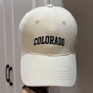 Détail macro d'une casquette de baseball en coton crème avec broderie COLORADO bleue