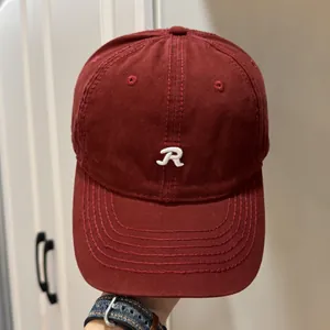 Gros plan sur une casquette de baseball bordeaux classique avec un logo R brodé blanc