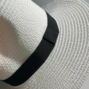 Close-up detail of white Panama straw hat texture with elegant black ribbon band.