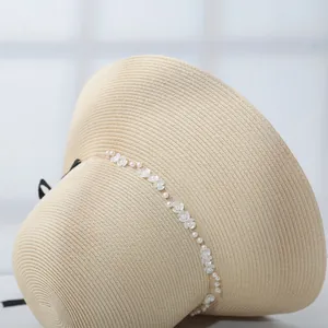 Exquisite close-up of pearl and flower decorations on a woven straw summer sun hat