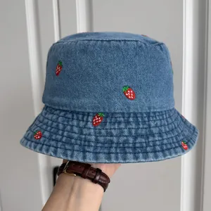 Close-up of blue denim bucket hat featuring high-quality red strawberry embroidery