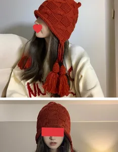 Detailansicht der roten Strickmütze mit Ohrenschutz und Quasten an einem Model