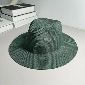 Detail shot of a dark green Panama straw hat with a fine woven texture and classic fedora crown.
