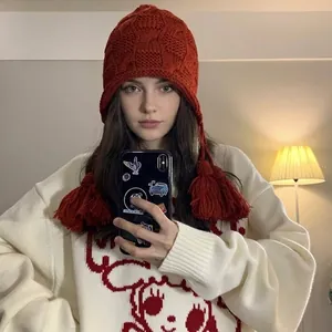 Warme rote handgestrickte Beanie-Mütze mit Ohrenklappen und Quasten für Damen im Winter