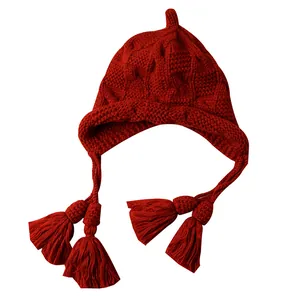 Rote Winterstrickmütze für Damen mit Quasten und Ohrenschutz im handgefertigten Wollstil.