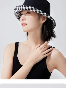 Detail showing a stylish black bucket hat with a checkered gingham brim on a model