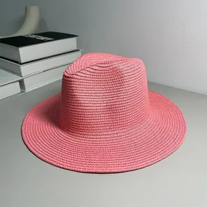 Side view detail of a pink woven Panama straw hat on a neutral background